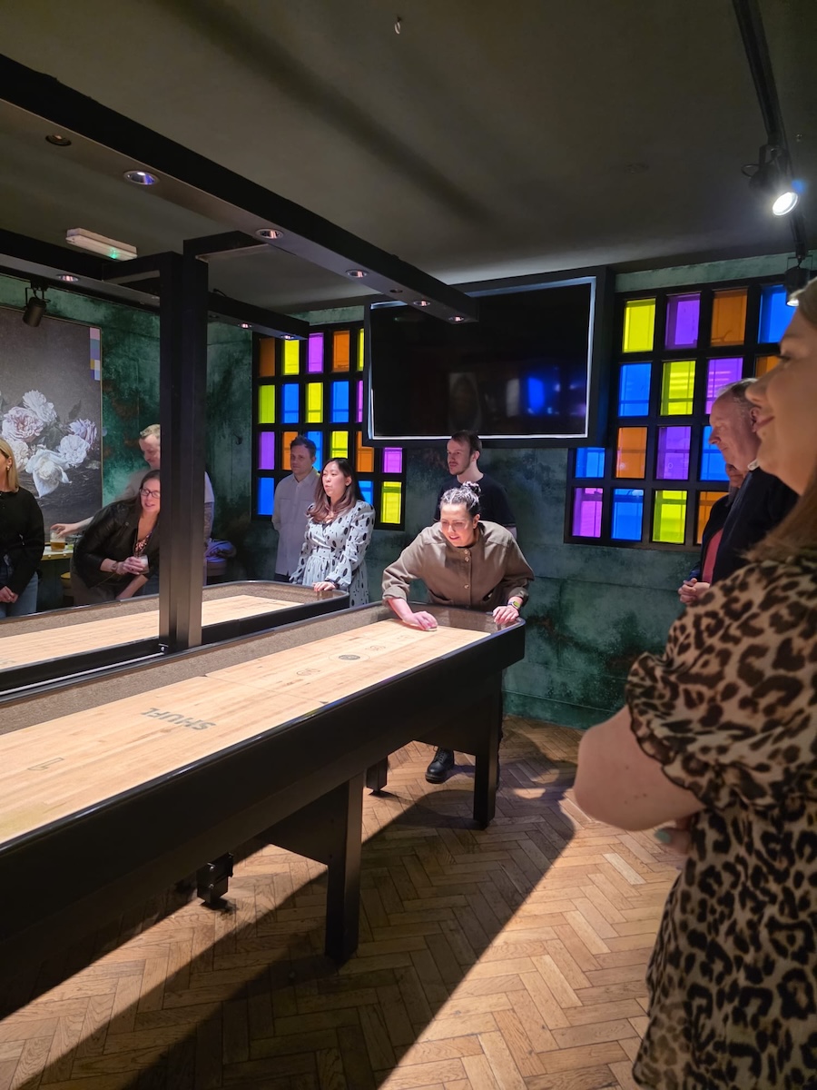 Members of the Fonemedia team play shuffle board together at a work event
